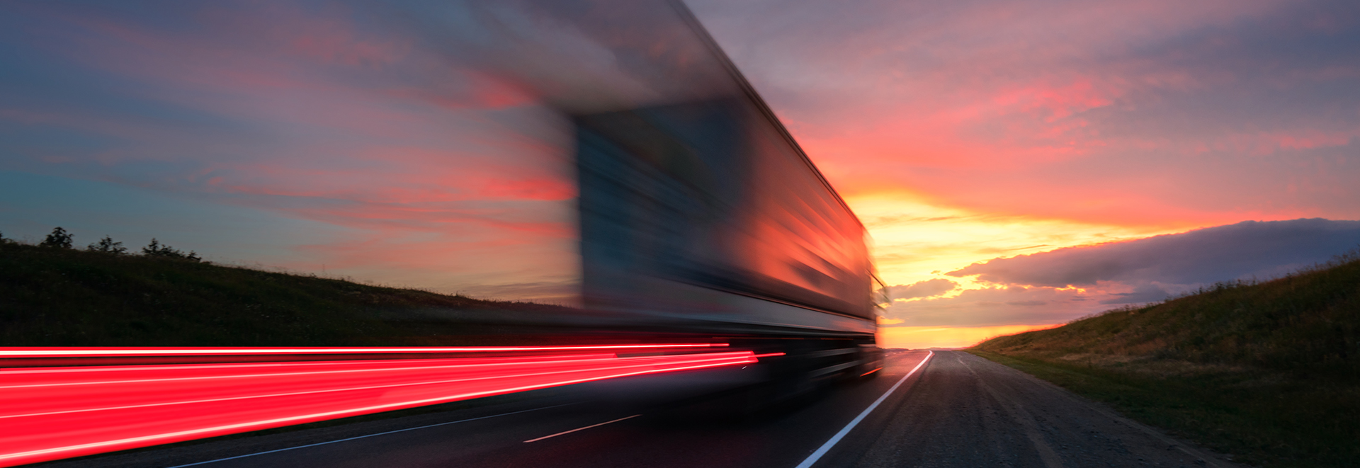 Motion blur. The truck is driving at high speed on the highway. Red Sky.